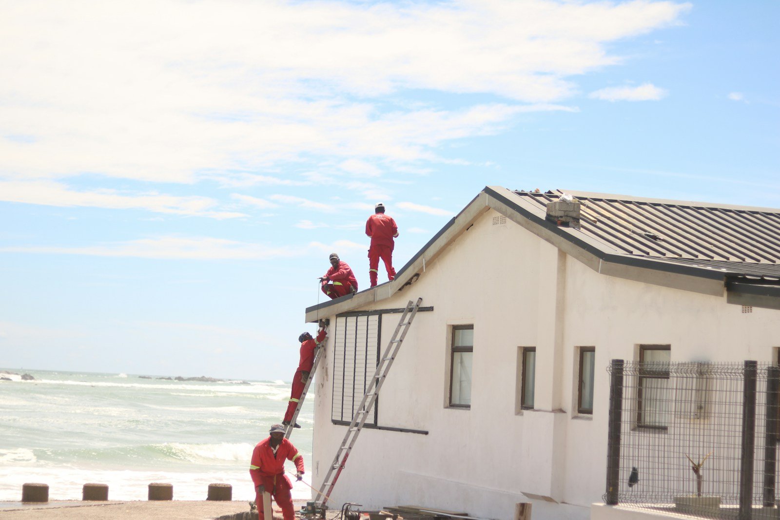 Workers in red suits on a white building roof