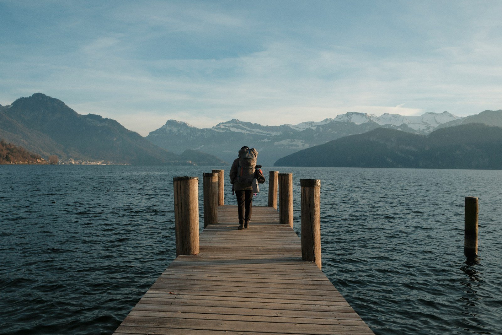 Woman walks on a pier towards mountains