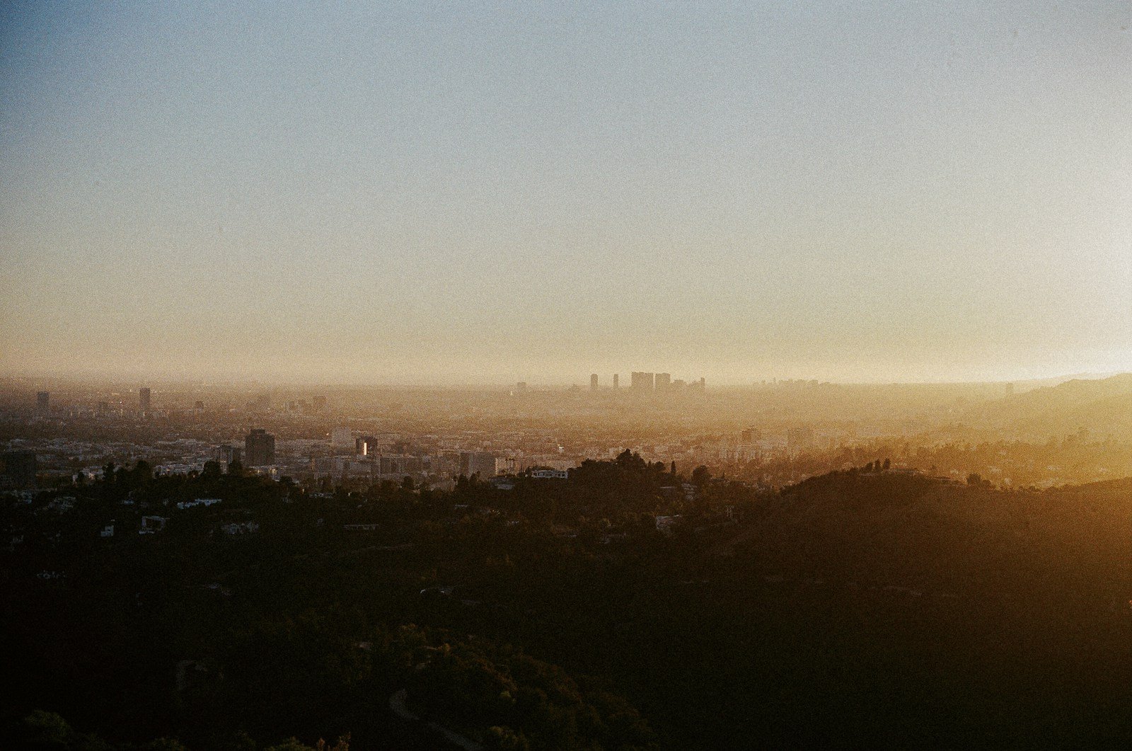 Hazy cityscape at sunrise with distant skyscrapers.