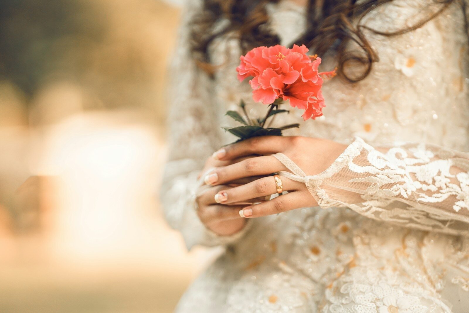 A woman in a white dress holding a red flower
