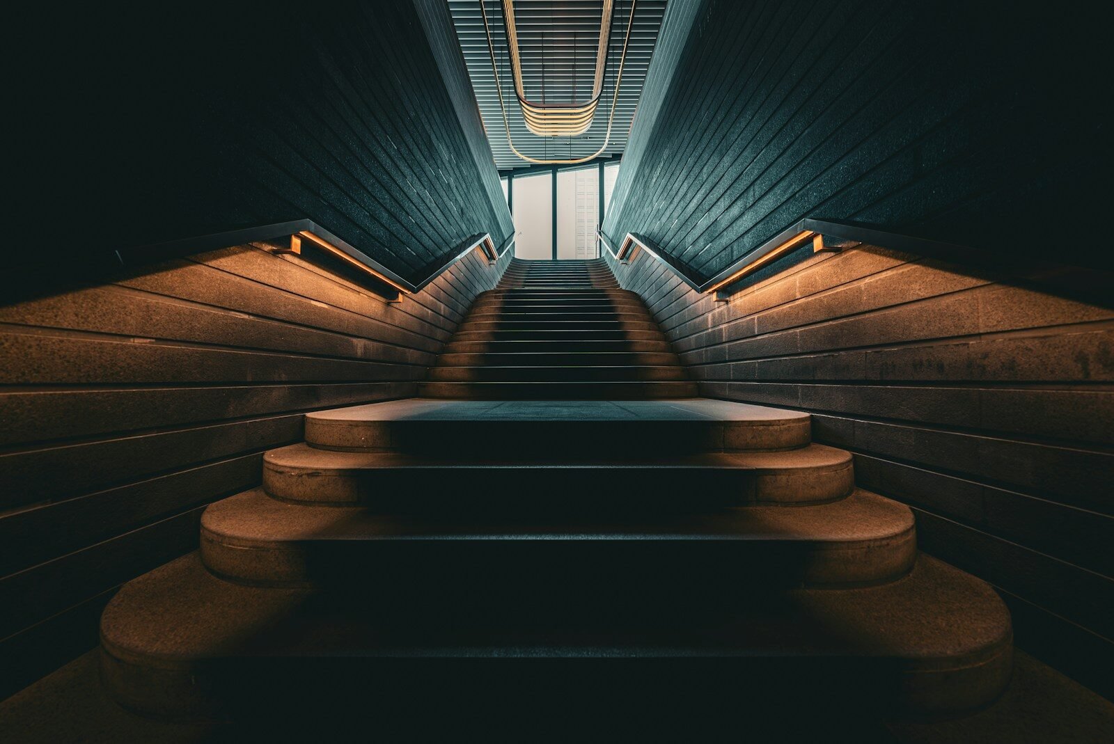 Concrete staircase with handrails leading to bright exit
