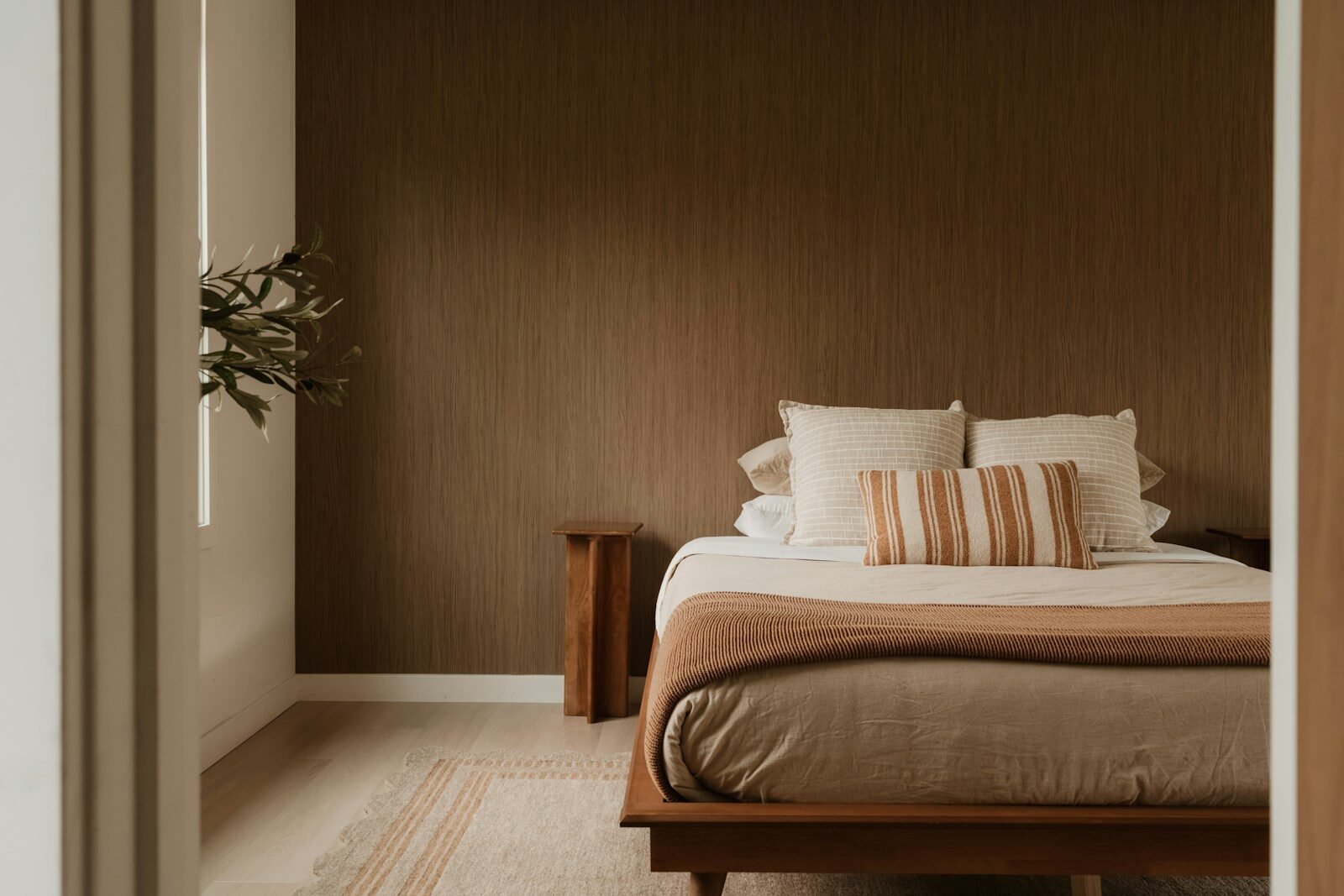 Modern bedroom with bed, pillows, and warm brown wall