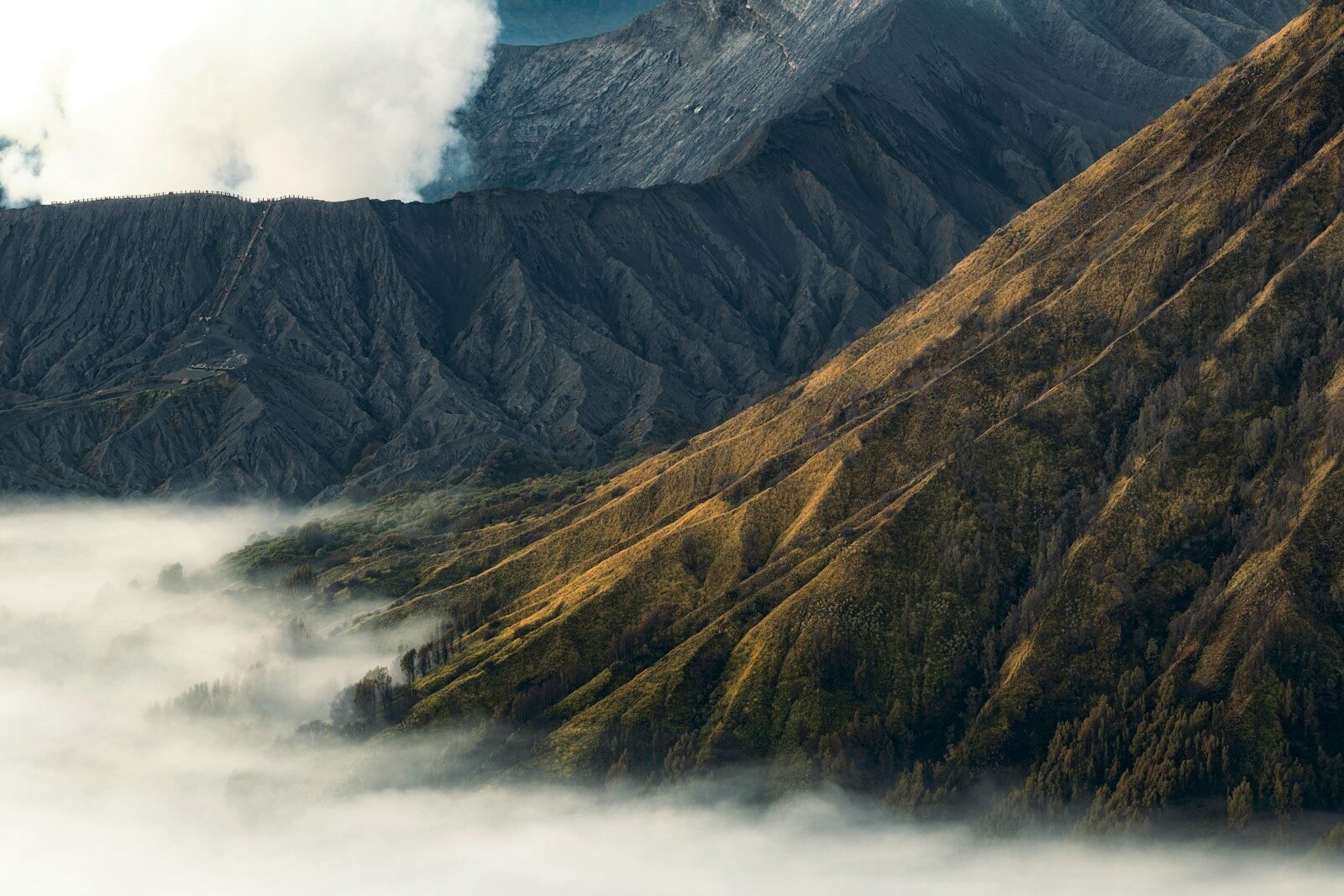 Rugged volcanic mountains partially obscured by low-lying clouds.