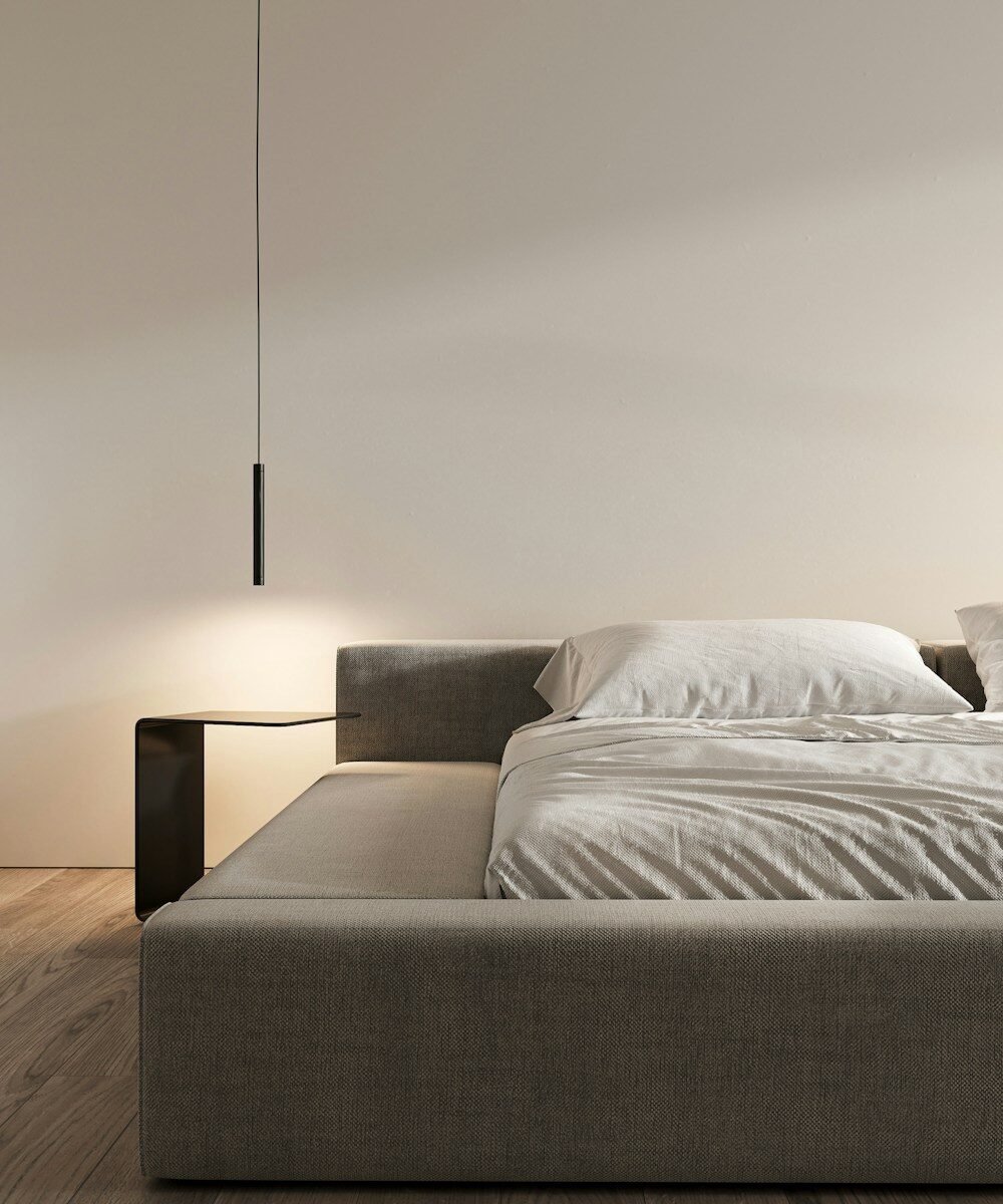 Contemporary bedroom with a gray bed and illuminated bedside table.