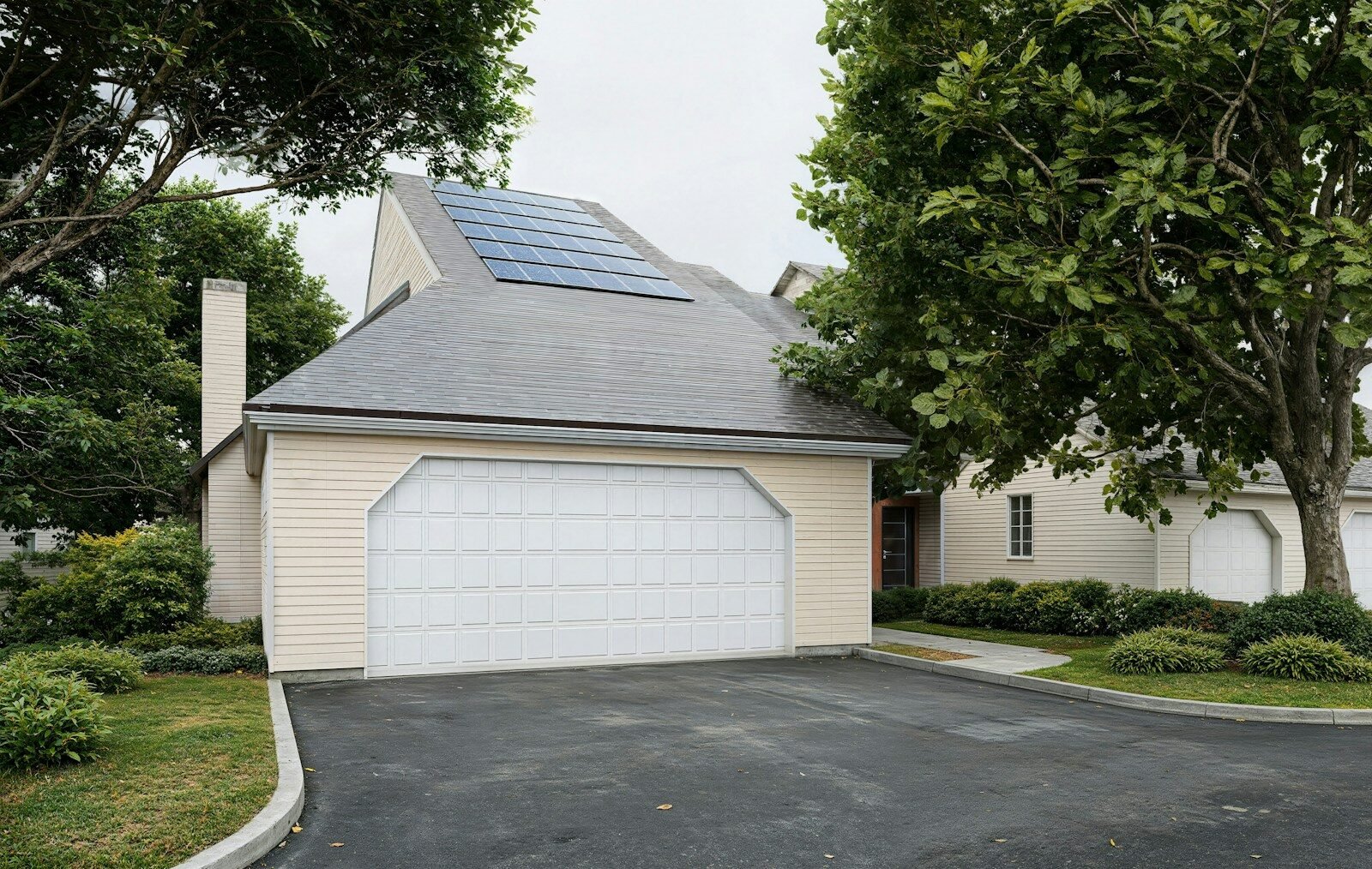 A house with solar panels, a garage, and green landscaping.